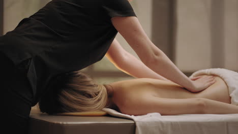 chiropractor-is-massaging-back-of-young-female-patient-in-massage-parlor-curing-and-preventing-scoliosis